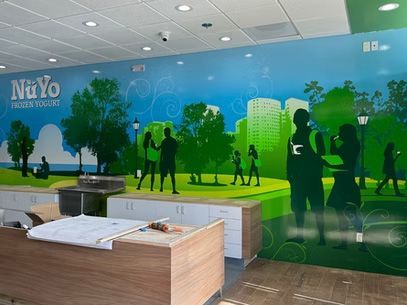 Office lobby with a blue-green mural, silhouettes of people, and a wooden reception desk