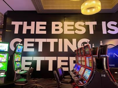 Casino wall sign reading “THE BEST IS GETTING BETTER” above colorful slot machines.