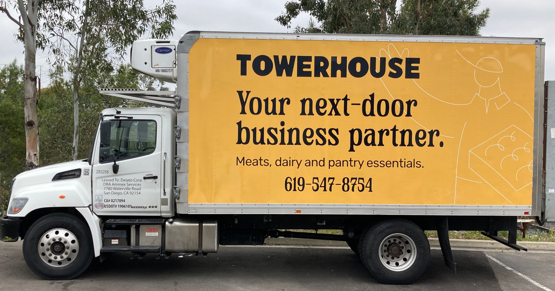 White box truck with yellow TOWERHOUSE ad panel parked outdoors.