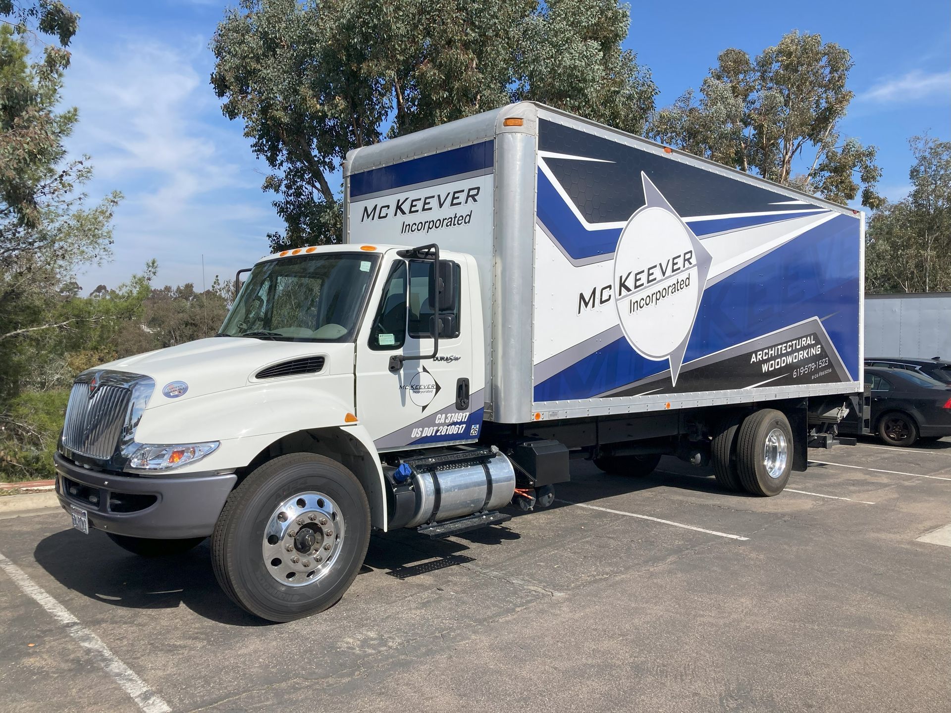 White McKevitt truck with blue graphics parked outdoors on a sunny day