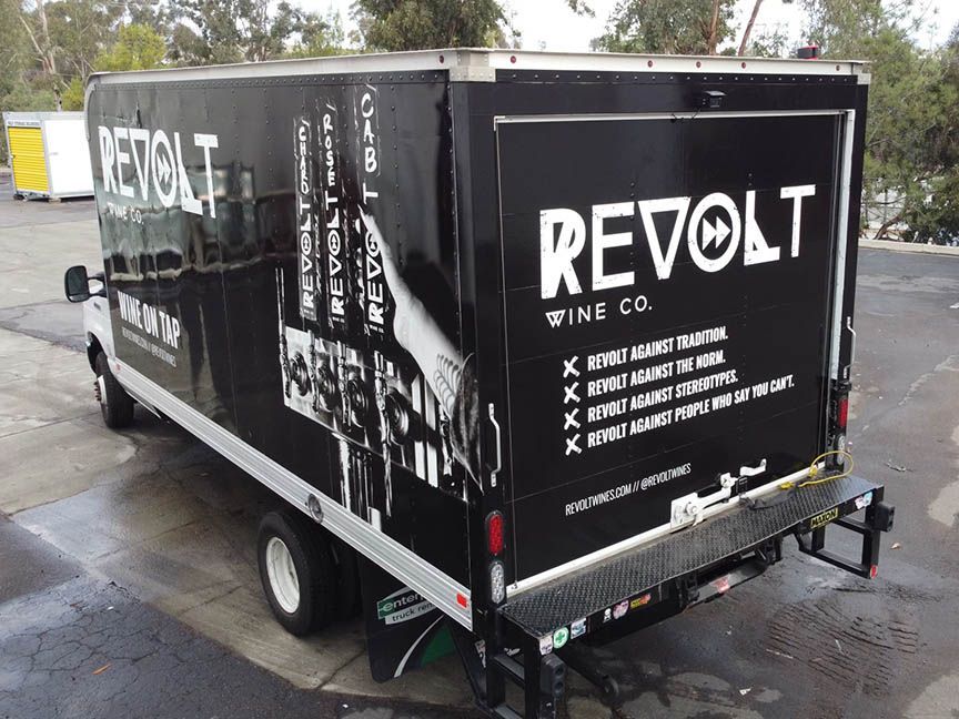 Black REVOlt wine company trailer parked outdoors on a wet lot