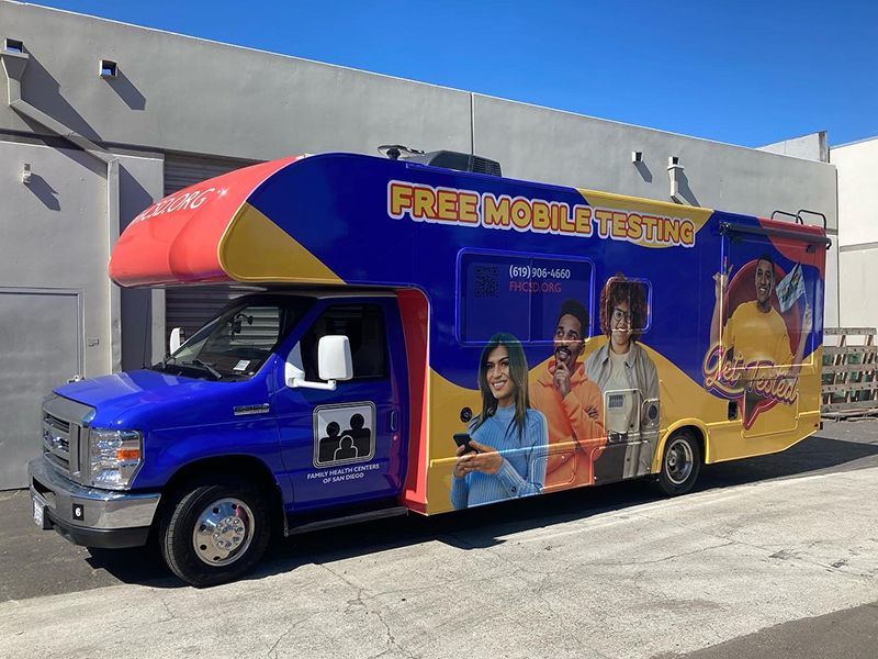 Blue mobile testing van with colorful “Free Mobile Testing” graphics parked outdoors