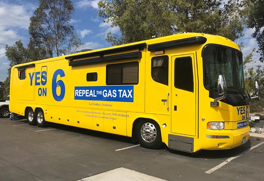 Yellow bus with “YES on 6” and “REPEAL GAS TAX” campaign graphics parked outdoors
