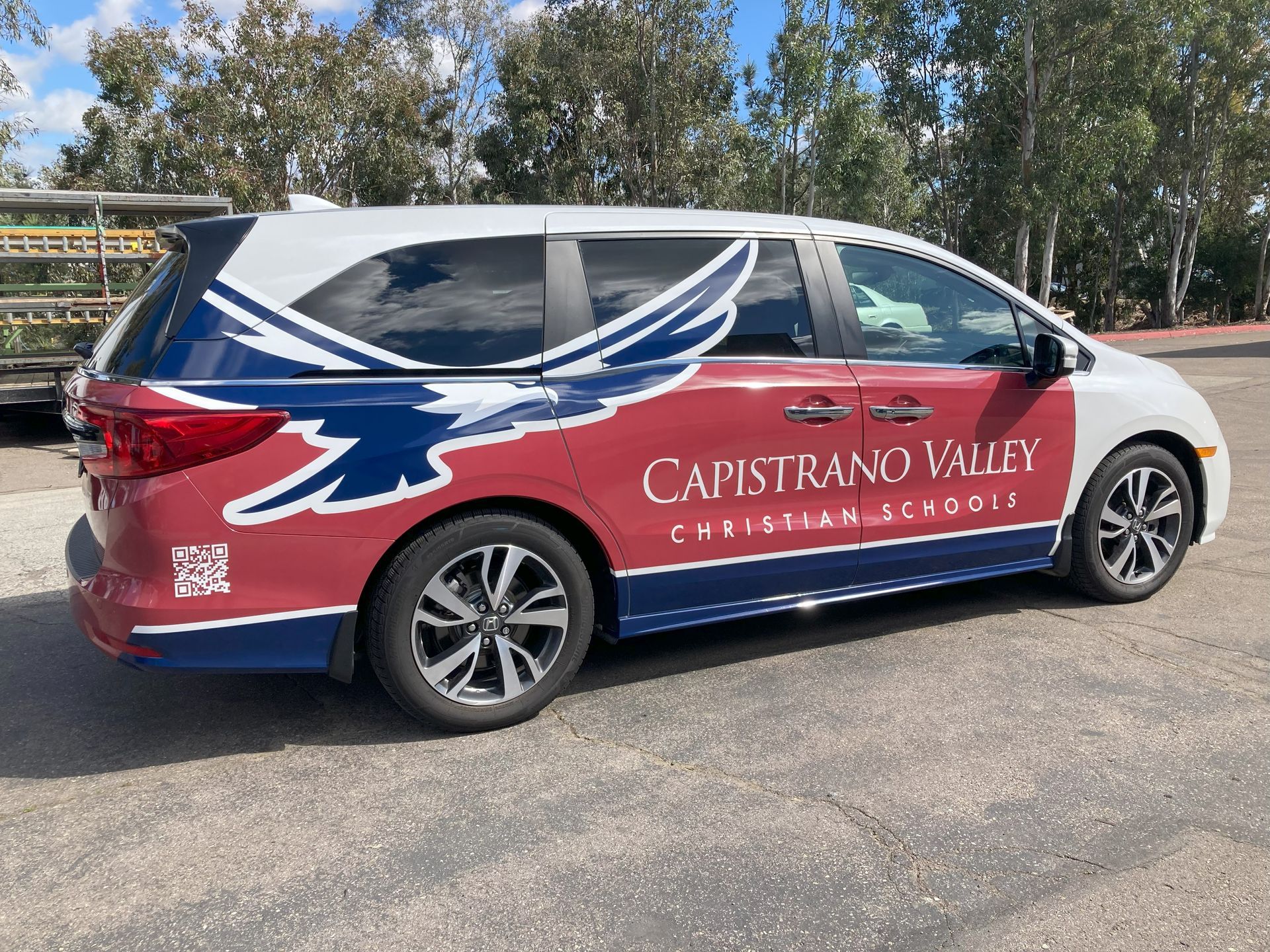 Red-and-white Capistrano Valley Christian Academy minivan with eagle graphic parked outdoors