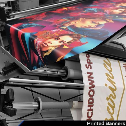 Large-format printer producing a colorful banner with illustrated faces and bold text on paper rolls