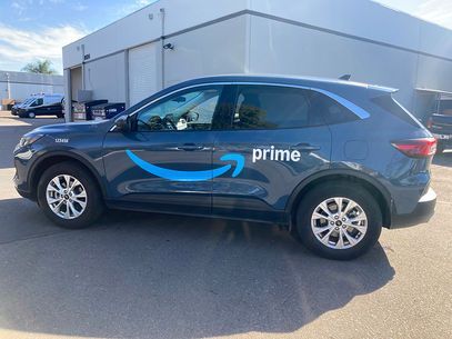 Black Amazon Prime SUV parked outside a warehouse building.