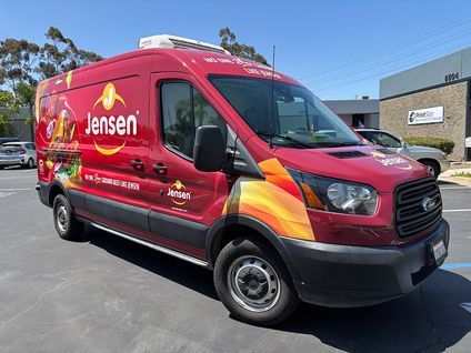 Red Jensen service van parked outside a building on a sunny day