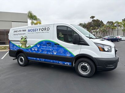 Mossy Ford service van with blue wave graphics and frog mascot parked outside a dealership