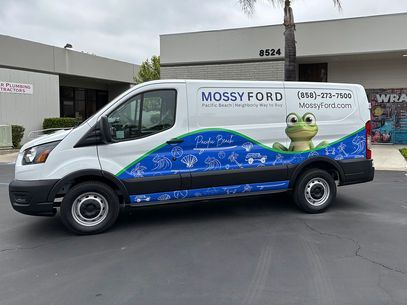 Mossy Ford service van with blue wave graphics parked outside a dealership building