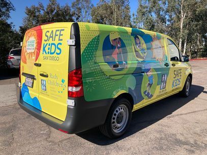 Yellow and green Safe Kids van with cartoon graphics parked outdoors in a lot