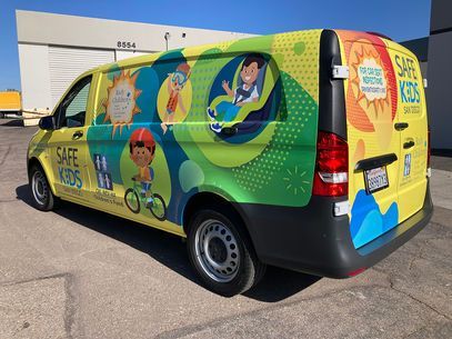 Colorful Safe Kids van with cartoon children graphics parked in a lot