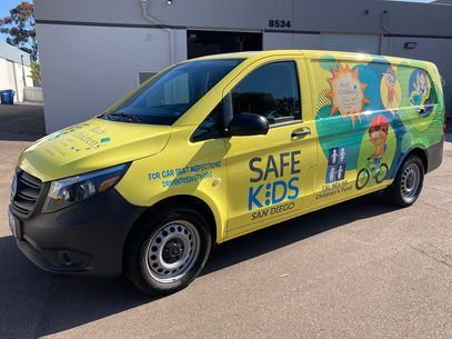 The yellow and black Safe Kids van parked outdoors, with colorful safety graphics on the side.