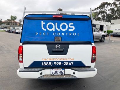 Rear view of a white Taos Pest Control pickup truck with blue branding and phone number