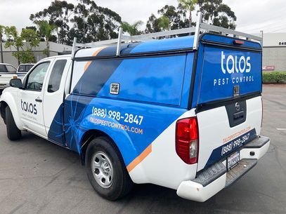 White and blue pest control service truck with TOLOS branding parked outdoors