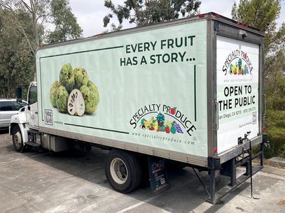 Specialty produce truck with fruit graphics and an Open to the Public sign on the side and rear.