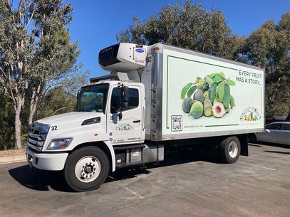 White refrigerated delivery truck with avocado graphics parked outdoors in a lot