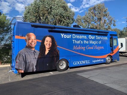 Blue Cox Communications truck with company slogan and two smiling people on the side, parked outdoors