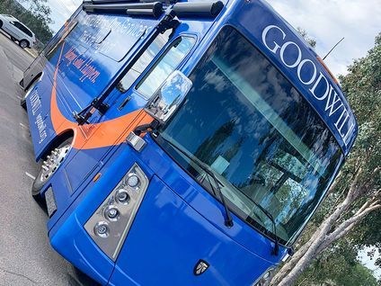Blue Goodman truck parked outdoors, angled view with orange accents and windshield reflections