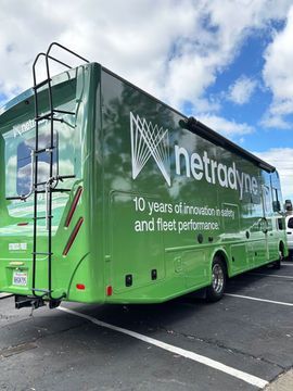 Green netravine-branded bus parked in a lot under a cloudy sky