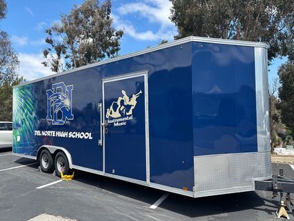 Blue horse trailer for a riding school parked outdoors under a sunny sky