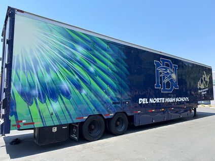 Blue Del Norte High School trailer with abstract green and blue wing design parked outdoors.
