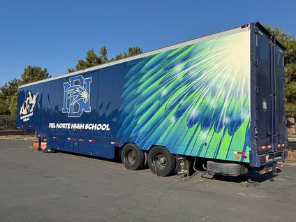 Blue trailer with a Northern High School logo and green swoosh graphic parked outdoors
