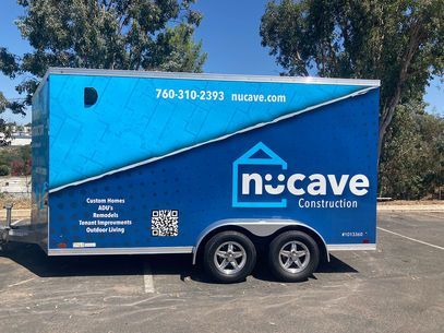 Blue Nucave Construction trailer parked outdoors with company logo, phone number, and QR code