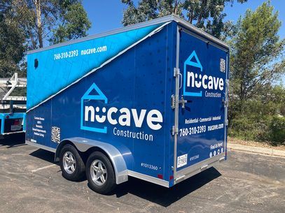 Blue Nucave Construction trailer parked outdoors on a sunny street.
