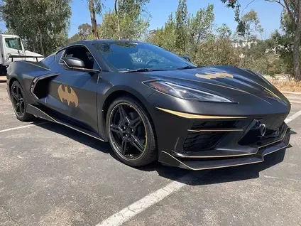 Black sports car with gold accents parked outdoors in a sunny lot