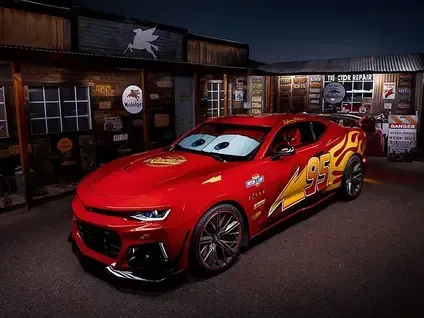 Red race car with cartoon eyes, parked outside a garage at night