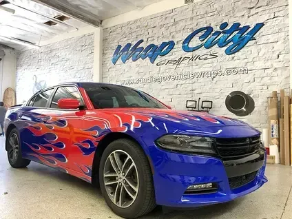 Blue sports car with red flame graphics parked in a Wrap City auto shop