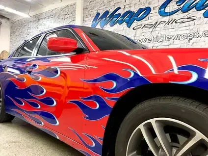 Custom red car with blue flame decals parked in a garage showroom