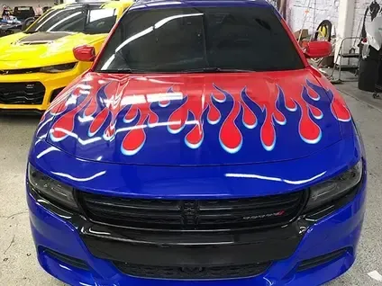 Blue car with red flame hood design, front view indoors