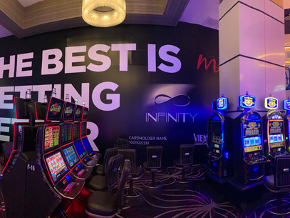 Casino slot machine area with neon-lit machines and a large wall sign.