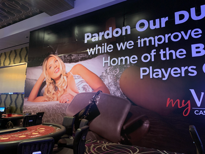 Casino ad mural with a woman reclining on a bed, glowing purple text, and slot machines in the foreground