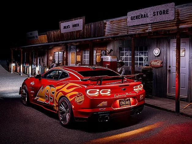 A red sports car is parked on a dimly lit old western-style street in front of a general store.