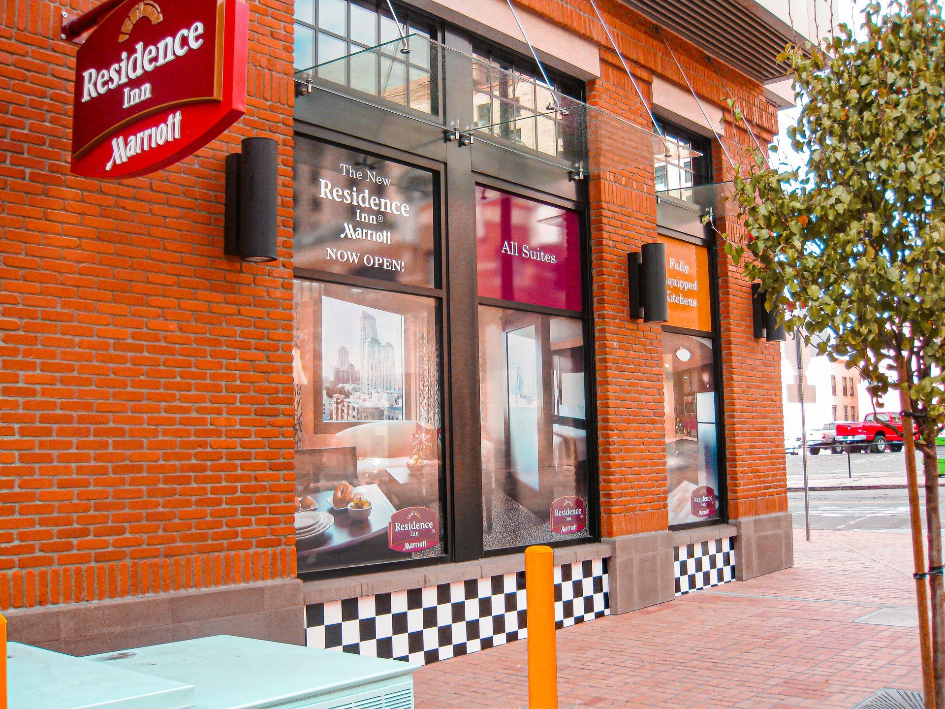 Residence Inn hotel entrance with red brick exterior and glass windows on a city sidewalk