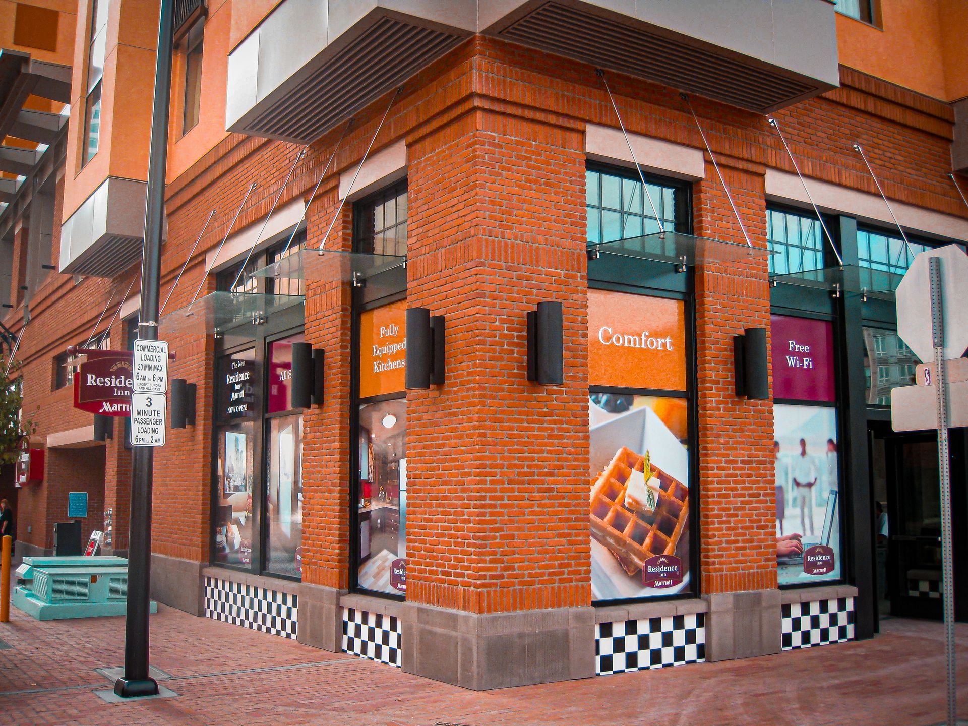 Corner street view of a brick restaurant with large windows and colorful menu signs