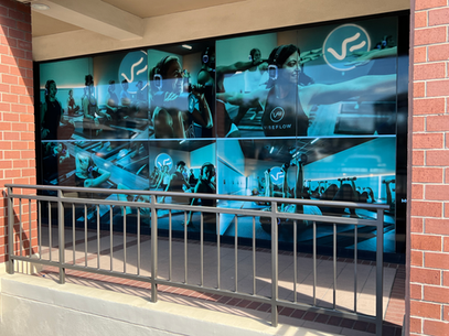 Blue-toned mural of athletes on a storefront wall behind a metal railing