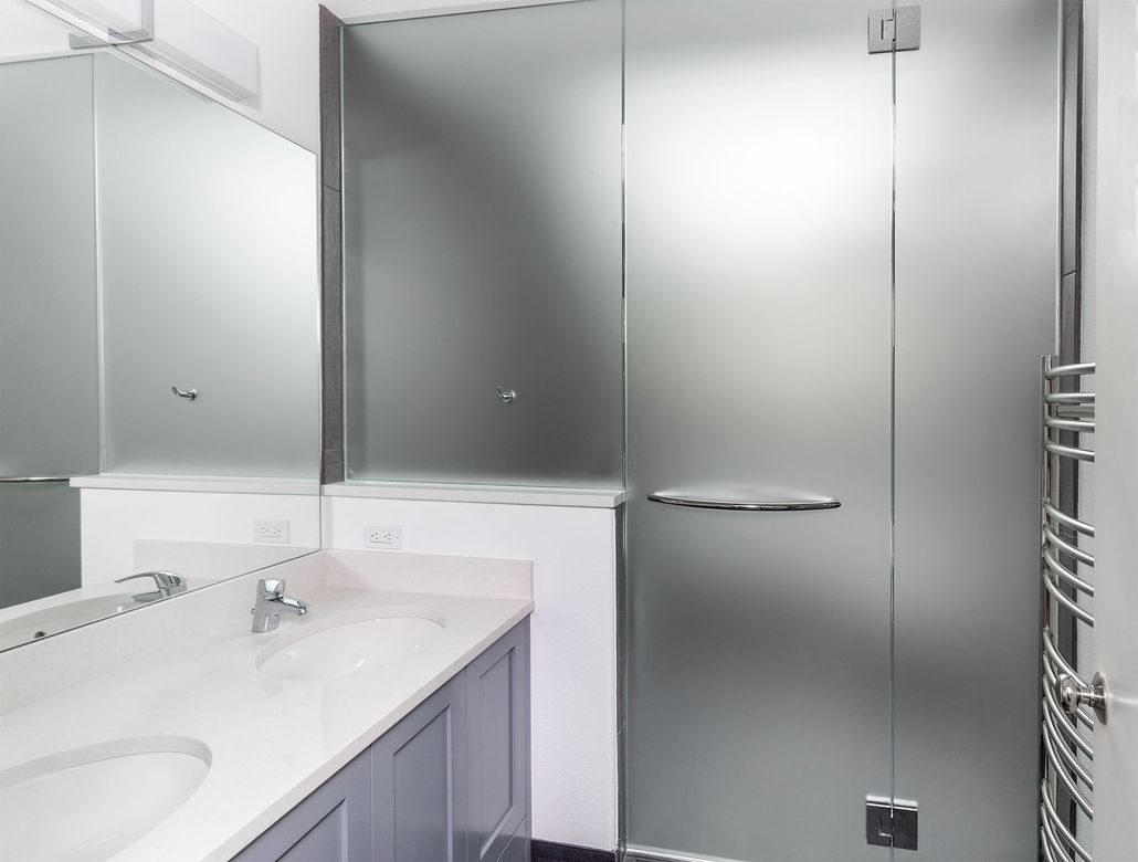 Modern bathroom vanity with a large mirror and frosted glass shower door