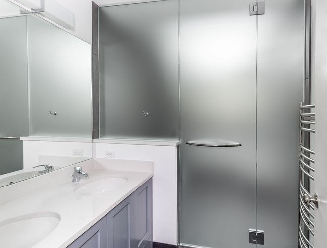 Modern bathroom vanity with a large mirror and frosted glass shower door