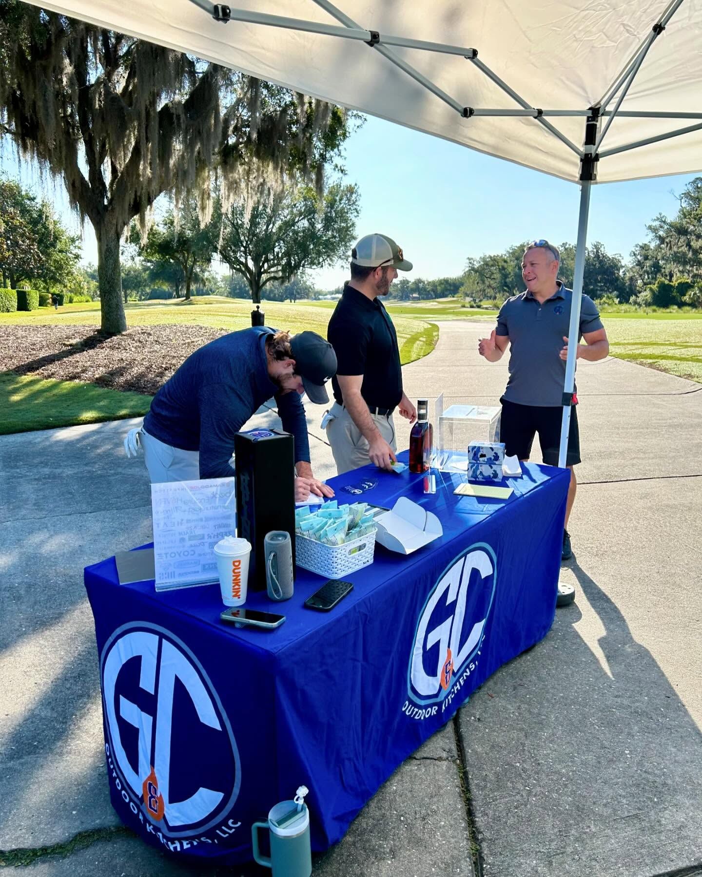People at a table under a canopy with the logo 