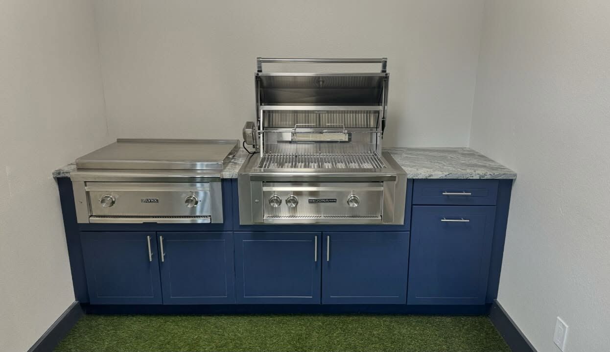 Outdoor kitchen with stainless steel grill, griddle, and blue cabinets.