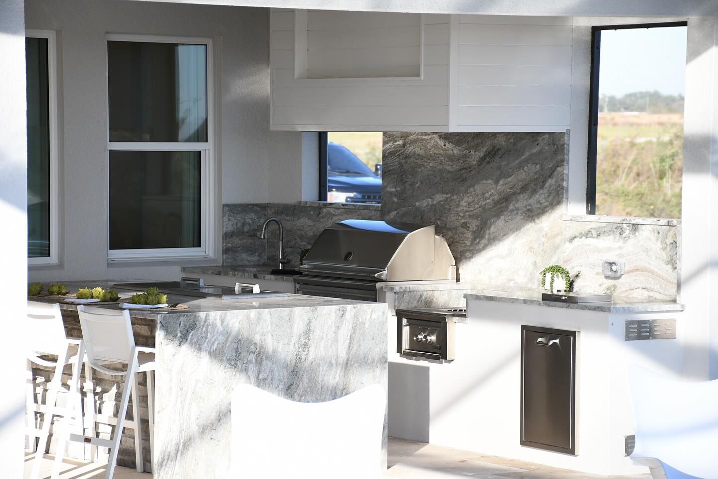 Outdoor kitchen with granite countertops, grill, and bar seating.