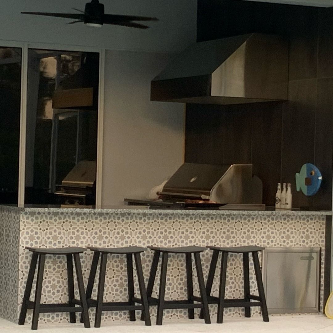 Outdoor kitchen with grill, stools, and range hood. Dark wood cabinetry and blue tile.