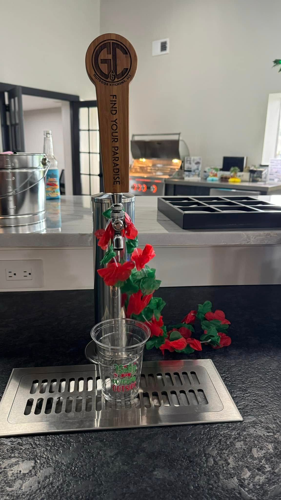Beer tap with red and green floral decorations over a glass, on a counter.
