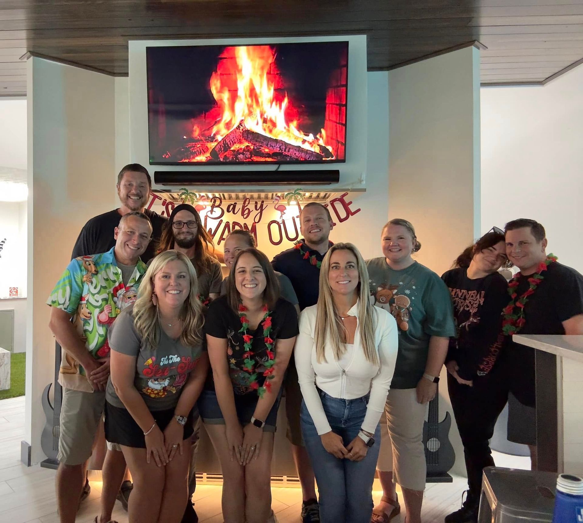 Group of people smiling, posing in front of a fireplace-themed display with a 