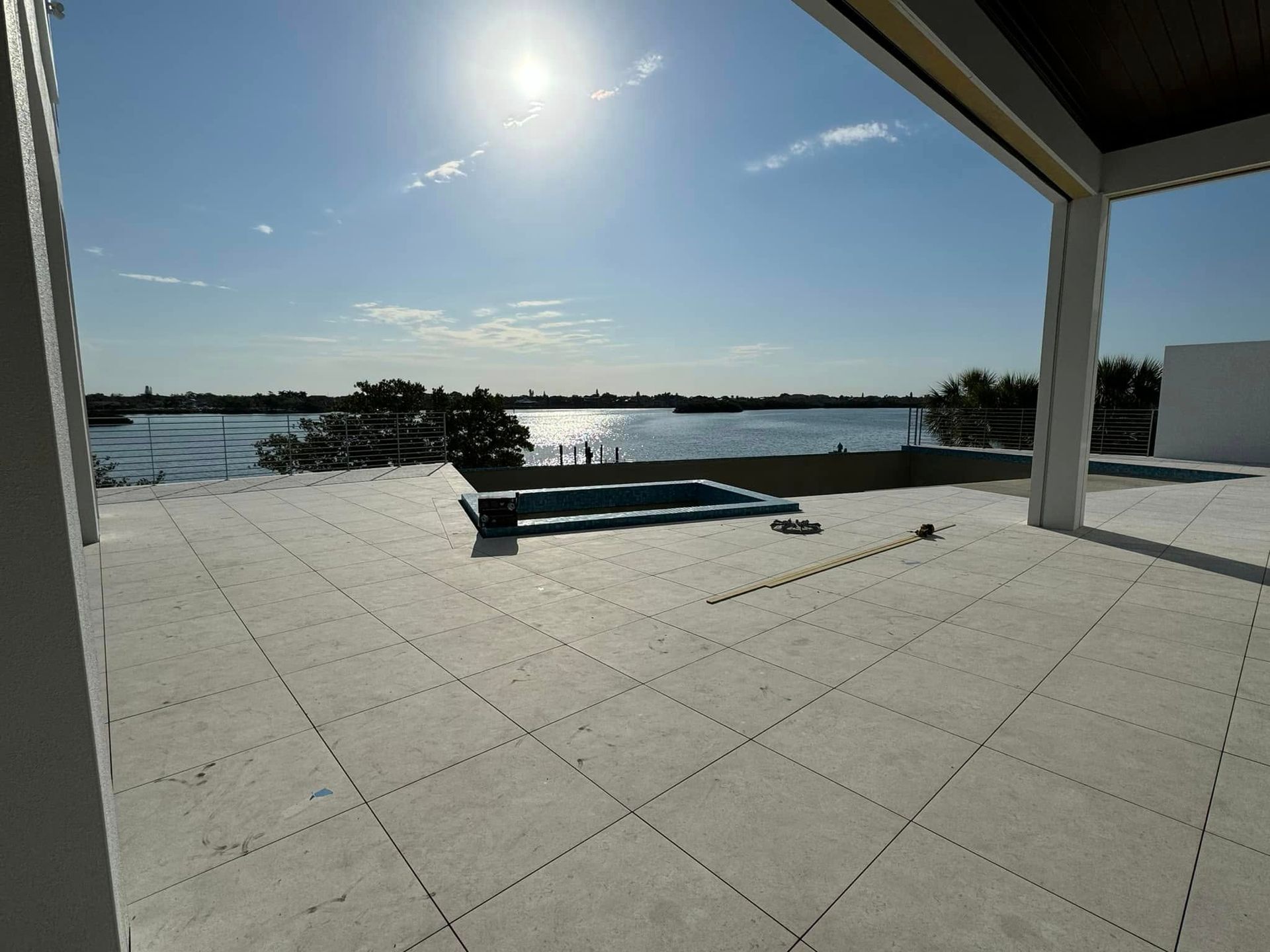 Rooftop with small pool, overlooking water, bright sun. Open-air structure with light-colored flooring.
