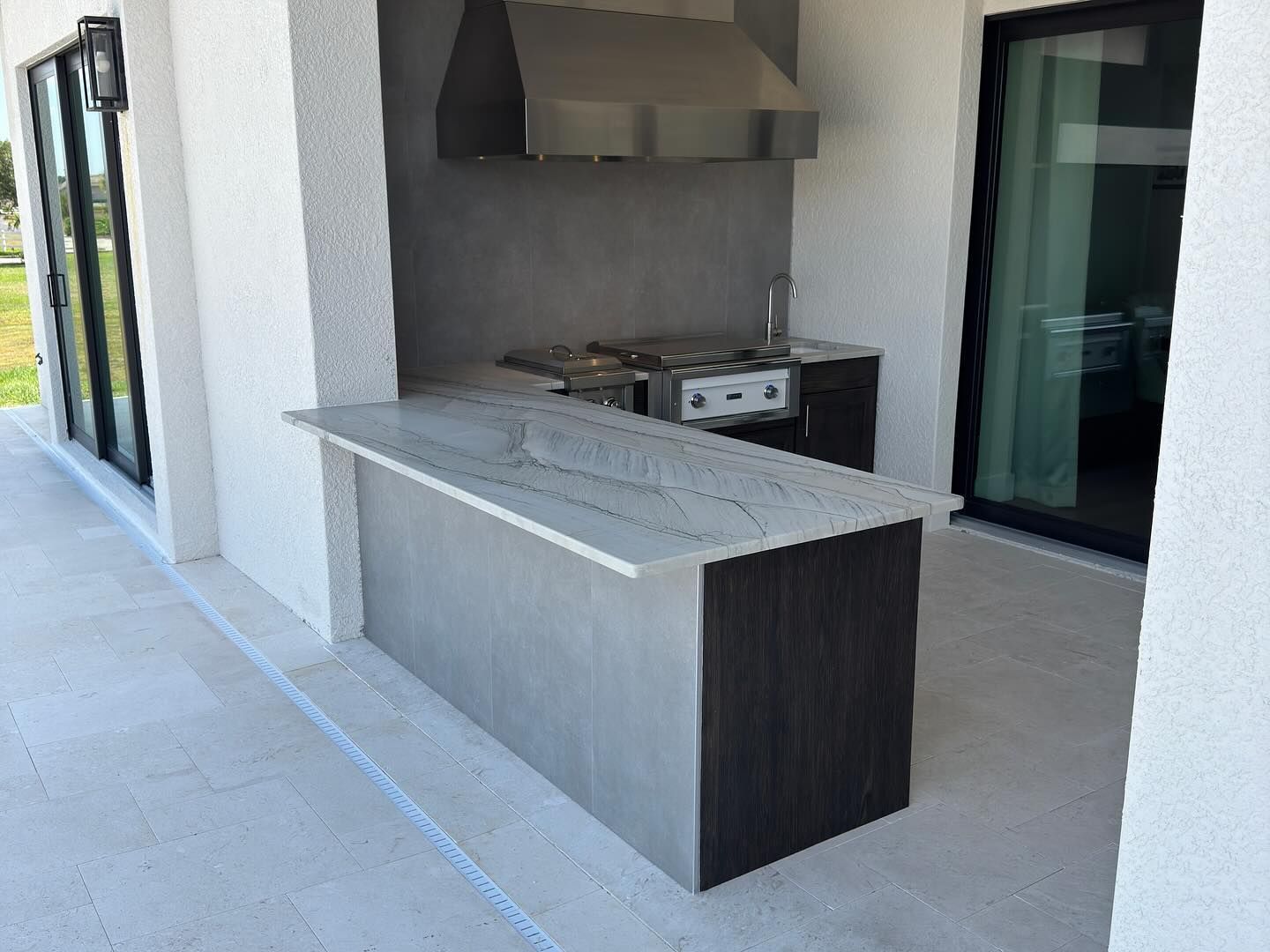 Outdoor kitchen with stainless steel appliances, dark wood cabinetry, and a granite countertop.