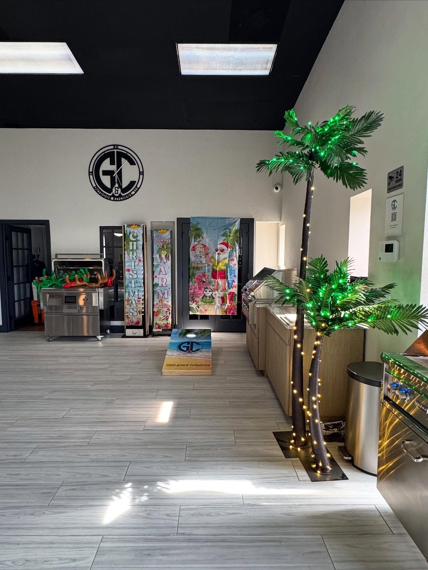 Interior shot of a business with vending machines, palm trees with lights, a cornhole set, and logo on wall.